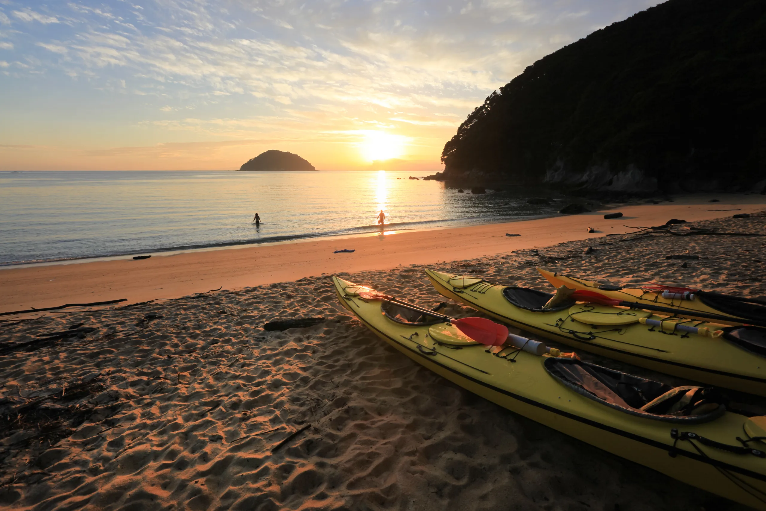 Sea kayaks drawn up on an Abel Tasman beach at sunrise