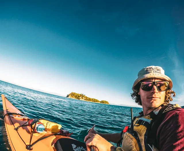 A Kahu paddler enjoying the open water beside a yellow kayak